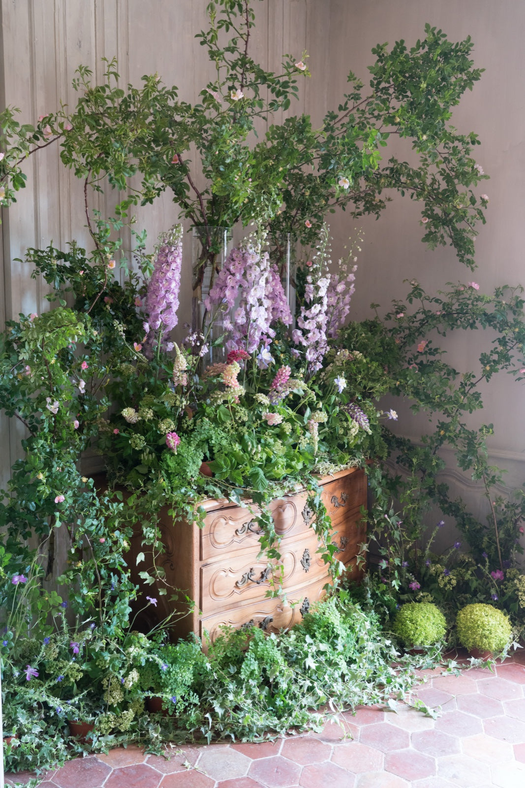 Delphinium, roses and ivy arranged on an old chest of drawers