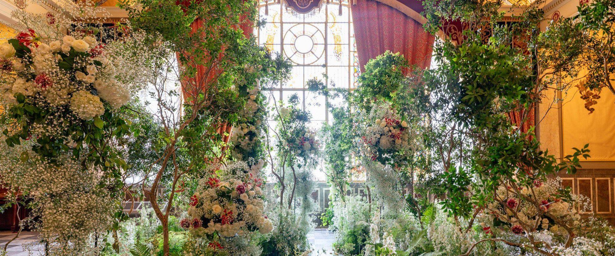 ステンドグラスの窓の下、広間いっぱいに生けられた白と緑の花
