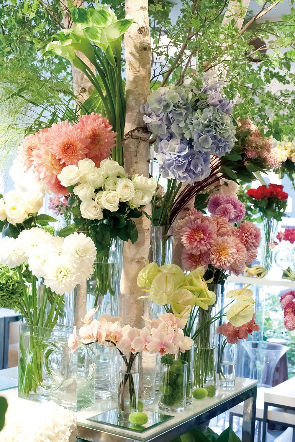 白樺の幹を囲んでガラスの器に花が並ぶ店内